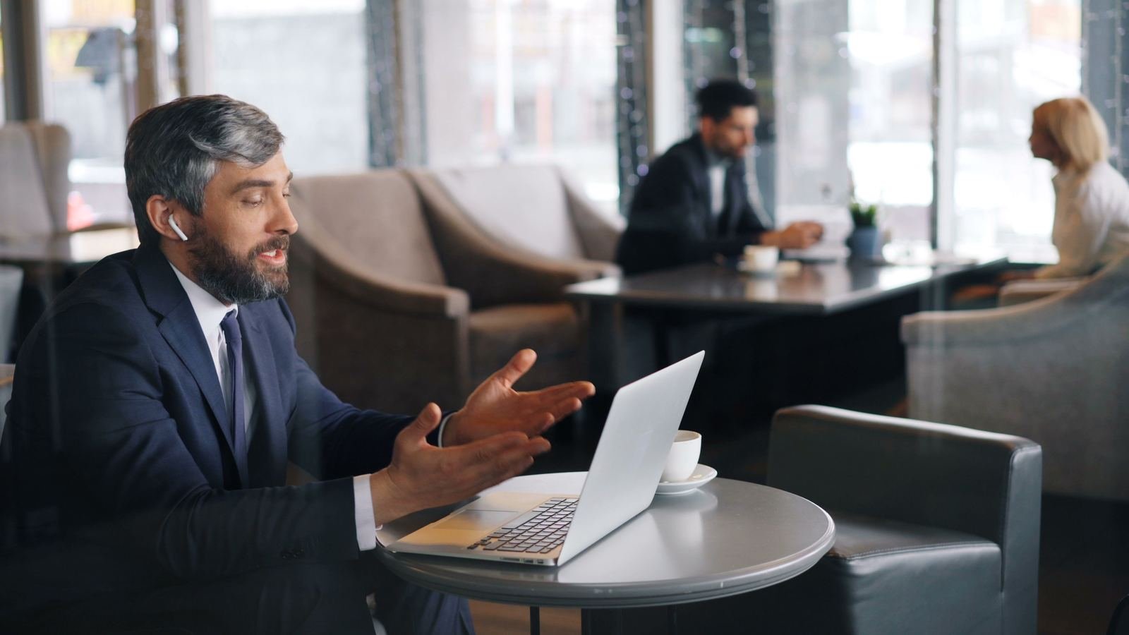 Un dirigeant en costume discute avec animation devant son ordinateur, dans un café d'affaires